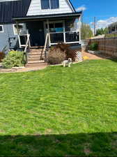 Summer time look of the back of house with a yard and covered porch