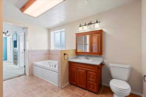 Bathroom featuring tile patterned flooring, vanity, toilet, a bath, and a textured ceiling