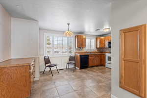 Kitchen with sink, black appliances, decorative backsplash, a textured ceiling, and decorative light fixtures