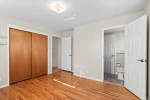 Unfurnished bedroom featuring ensuite bath, a closet, and light wood-type flooring