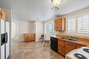 Kitchen with sink, decorative light fixtures, a textured ceiling, white appliances, and decorative backsplash