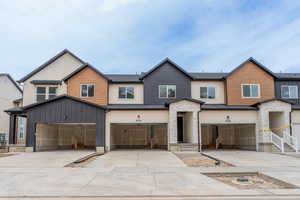 Multi unit property with driveway, an attached garage, and stone siding
