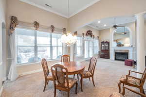 Dining room featuring ornamental molding, ceiling fan with notable chandelier, and light carpet