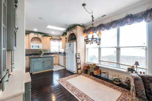 Kitchen with a skylight, a chandelier, dark hardwood / wood-style flooring, pendant lighting, and white appliances