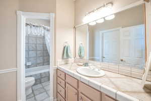 Bathroom featuring vanity, toilet, and tiled tub