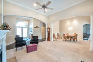 Living room featuring ornate columns, a towering ceiling, ornamental molding, carpet, and french doors