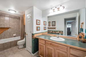 Full bathroom with vanity, shower / tub combo, tile patterned flooring, and toilet