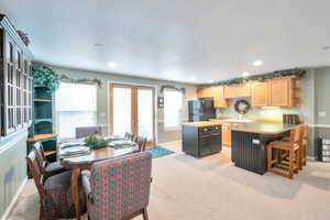 Kitchen featuring a kitchen island, black refrigerator, light carpet, and french doors