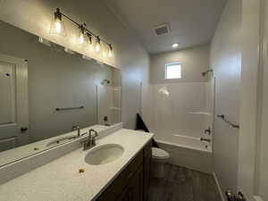 Full bathroom featuring hardwood / wood-style flooring, vanity, washtub / shower combination, and toilet