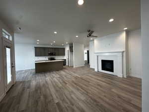 Unfurnished living room with a brick fireplace, dark hardwood / wood-style floors, and ceiling fan