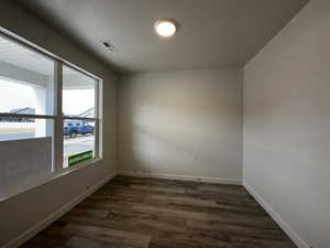 Empty room featuring dark wood-type flooring and a textured ceiling