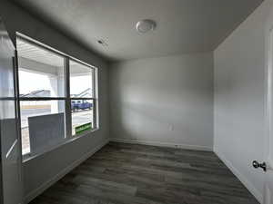 Unfurnished room with dark hardwood / wood-style floors and a textured ceiling