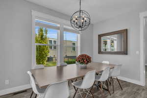 Dining space featuring LVP flooring, plenty of natural light, and a chandelier