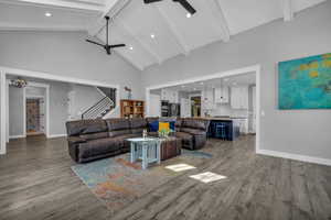 Great room with beamed ceiling, high vaulted ceiling, ceiling fan, and light LVP flooring