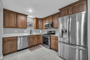 Basement MIL apartment with appliances with stainless steel finishes, sink, and light tile patterned floors