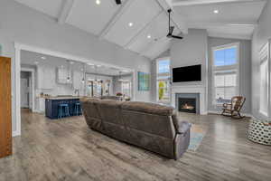 Great room with beam ceiling, ceiling fan, light LVP flooring, and high vaulted ceiling