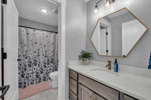 Bathroom with vanity, tile patterned flooring, toilet and tub/shower combo