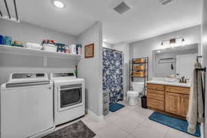 MIL apartment combined laundry room and bathroom featuring light tile patterned floors, sink, washer and dryer