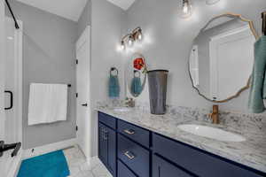 Primary bathroom with tile patterned flooring and vanity with quartz countertops, separate shower and tub not pictured