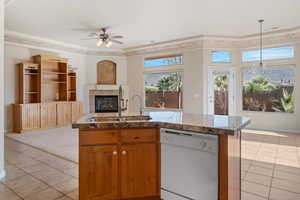 Kitchen featuring pendant lighting, sink, a tile fireplace, white dishwasher, and light tile patterned flooring