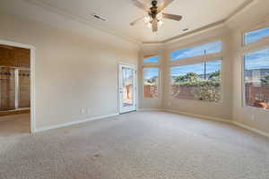 Spare room with a towering ceiling, light carpet, ceiling fan, and a tray ceiling