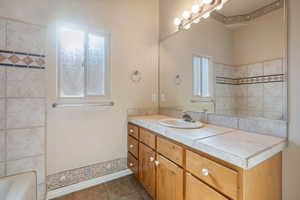 Bathroom featuring a healthy amount of sunlight, tile patterned floors, bathing tub / shower combination, and vanity