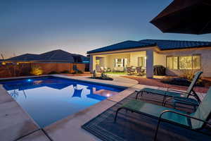 Pool at dusk with area for grilling and a patio area