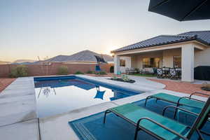 Pool at dusk featuring a patio and a grill