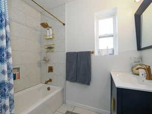 Bathroom with shower / bath combination with curtain, tile patterned floors, and vanity