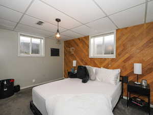 Carpeted bedroom featuring a drop ceiling and wood walls