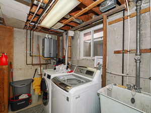 Laundry room with water heater, sink, and washing machine and clothes dryer