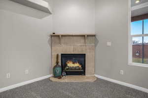 Room details with a tiled fireplace and carpet floors