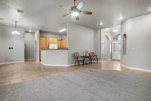 Living room featuring ceiling fan, a textured ceiling, and light tile patterned floors