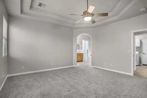 Unfurnished room with ceiling fan, light colored carpet, a raised ceiling, and washing machine and dryer