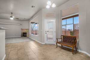 Interior space featuring a tiled fireplace, light tile patterned floors, and ceiling fan