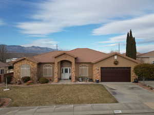 Ranch-style house featuring a mountain view, a garage, and a front yard