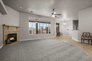 Unfurnished living room featuring a tiled fireplace, light tile patterned floors, a textured ceiling, and ceiling fan