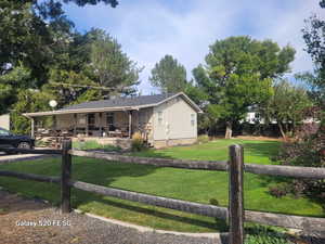 Ranch-style home featuring covered porch and a front lawn