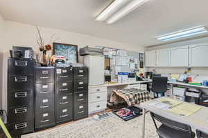 Office area with light hardwood / wood-style floors and a textured ceiling