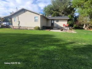 Back of house featuring a yard, central AC, and a patio