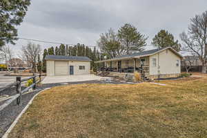 View of front of property with an outbuilding, a garage, a front lawn, and a porch