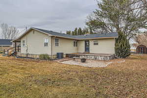 Rear view of property featuring central AC unit and a lawn