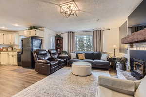 Living room with a chandelier, a textured ceiling, and light hardwood / wood-style floors