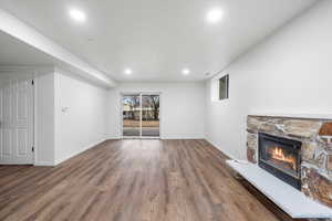 Unfurnished living room featuring hardwood / wood-style flooring and a stone fireplace