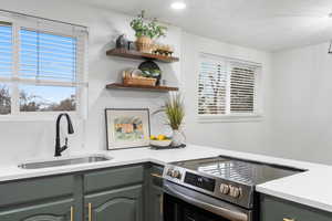 Kitchen featuring stainless steel electric stove, sink, and backsplash