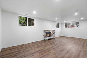 Unfurnished living room with a stone fireplace and hardwood / wood-style floors