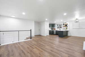 Kitchen with hardwood / wood-style floors, sink, a kitchen breakfast bar, stainless steel dishwasher, and kitchen peninsula