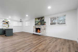 Unfurnished living room with hardwood / wood-style flooring and a stone fireplace