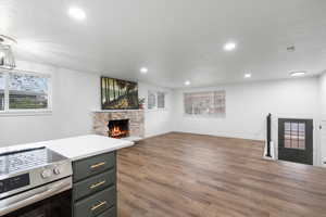 Living room with dark wood-type flooring, a healthy amount of sunlight, a fireplace, and a textured ceiling