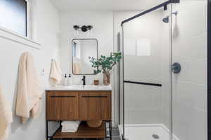 Bathroom with an enclosed shower, vanity, and plenty of natural light